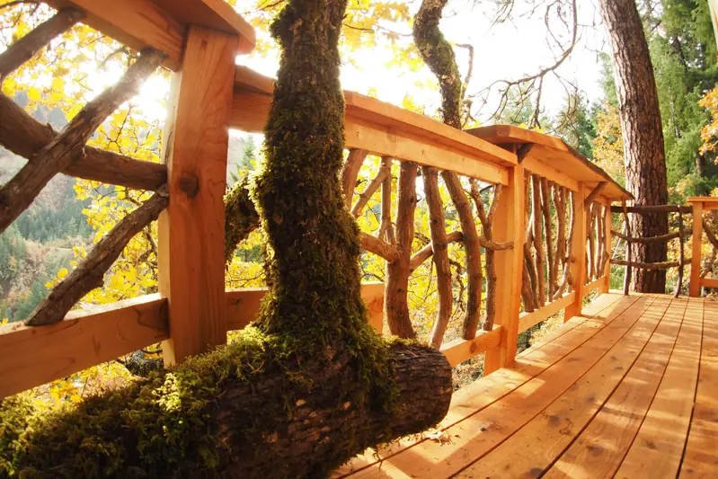 Deck railing built from branch work, with a moss-covered oak limb running through the deck and the valley beyond